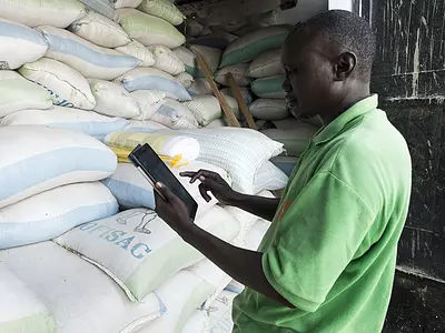 A technician checks the stock with a tablet at Aïssatou GAYE's mini rice company in Richard Toll town, Senegal. Photo by Xaume Olleros / RTI