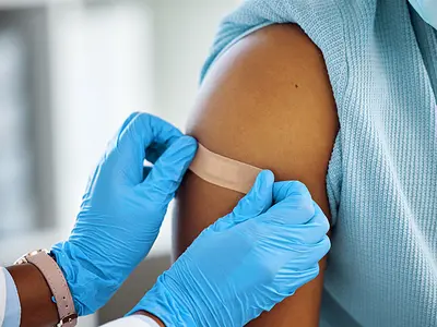 Health care worker applies band-aid post-vaccination
