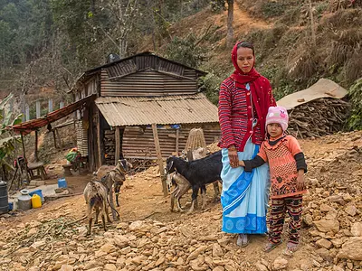 A female community health volunteer with her daughter in front of their home in Nepal.