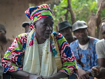 Two women and a man talk during a governance-related meeting in Guinea.