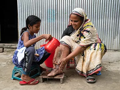 young girl helps wash an elder in Bangladesh