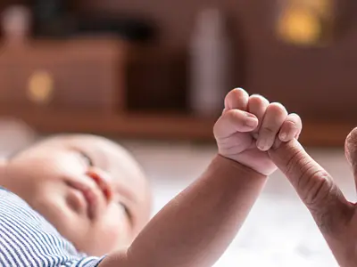 A closeup photo of a baby holding an adult's pinky