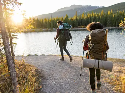 Photo of two backpackers hiking near a lake