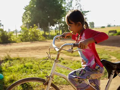 Photo of a young girl outside riding her bike