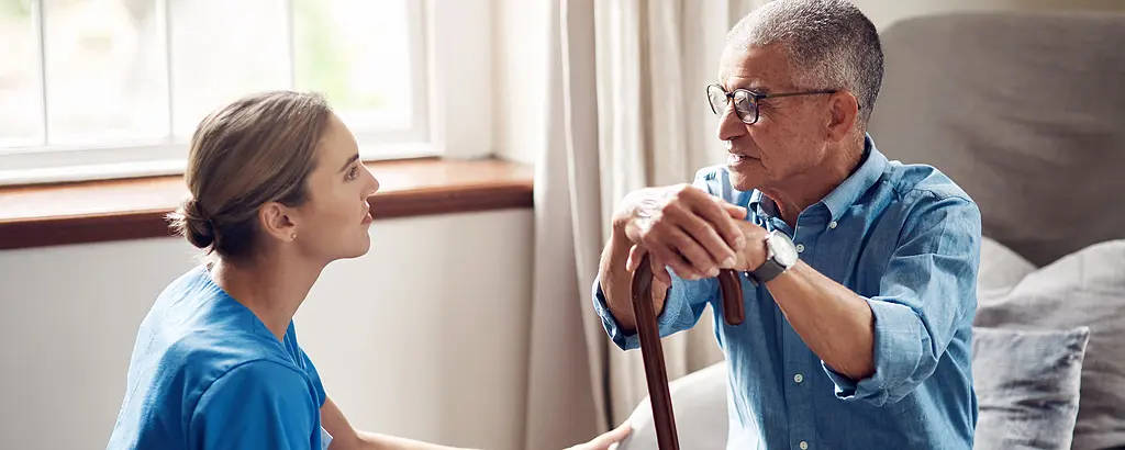 A female health care worker visits a senior male patient at his home.