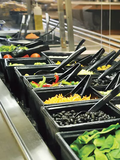A customer selects food from a salad bar