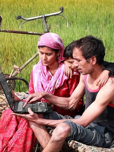 A family uses a laptop in a field