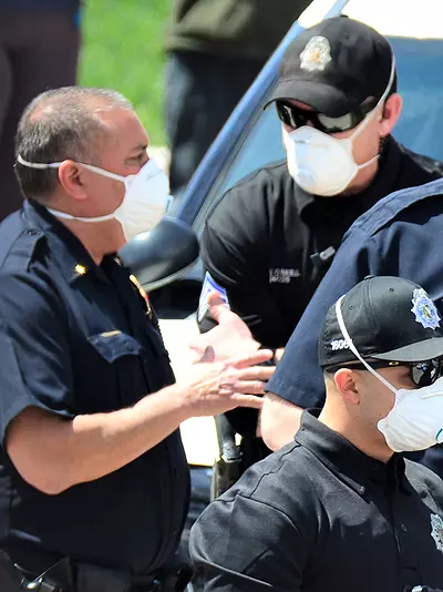 a group of police officers on scene are all wearing protective masks due to the COVID-19 pandemic