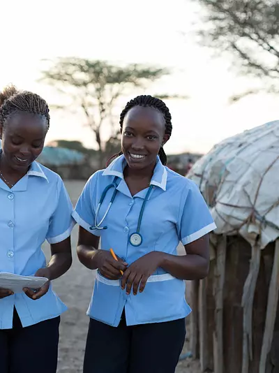 Two African nurses in a village smiling