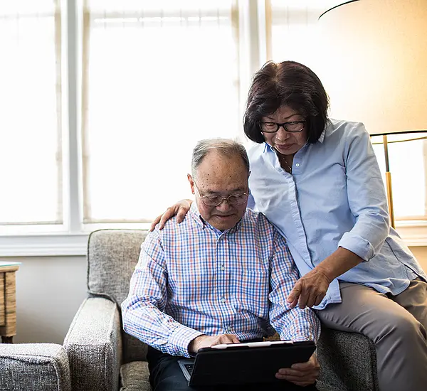 A senior Asian man and woman read news together on a tablet.