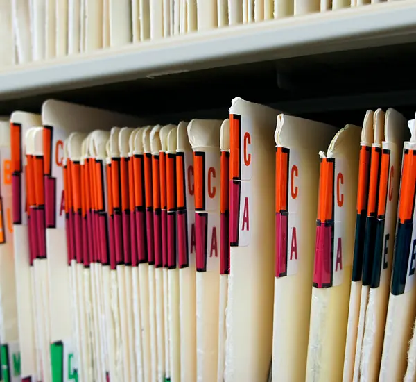 A row of alphabetized medical records on a shelf