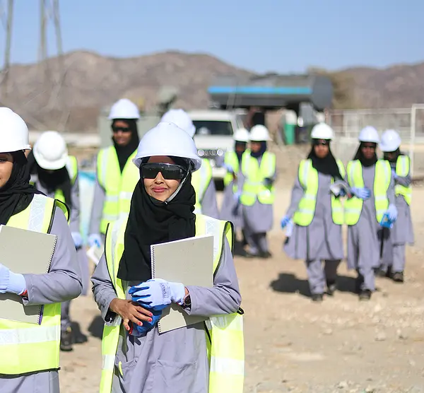 Women in hardhats walk through a solar energy installation during the Somalia GEEL project.