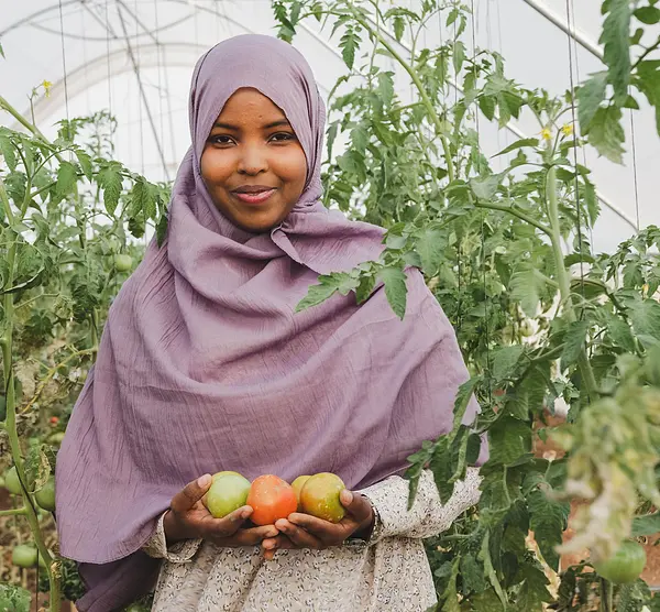 A Somali girl holds samples of fruit from an orchard.
