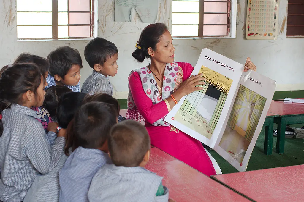 A teacher reads to a group of students from a book provided by the EGRP in Nepal.
