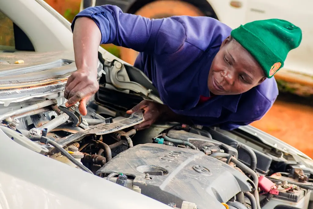 A female mechanic works on a car engine in Bungoma, Kenya.