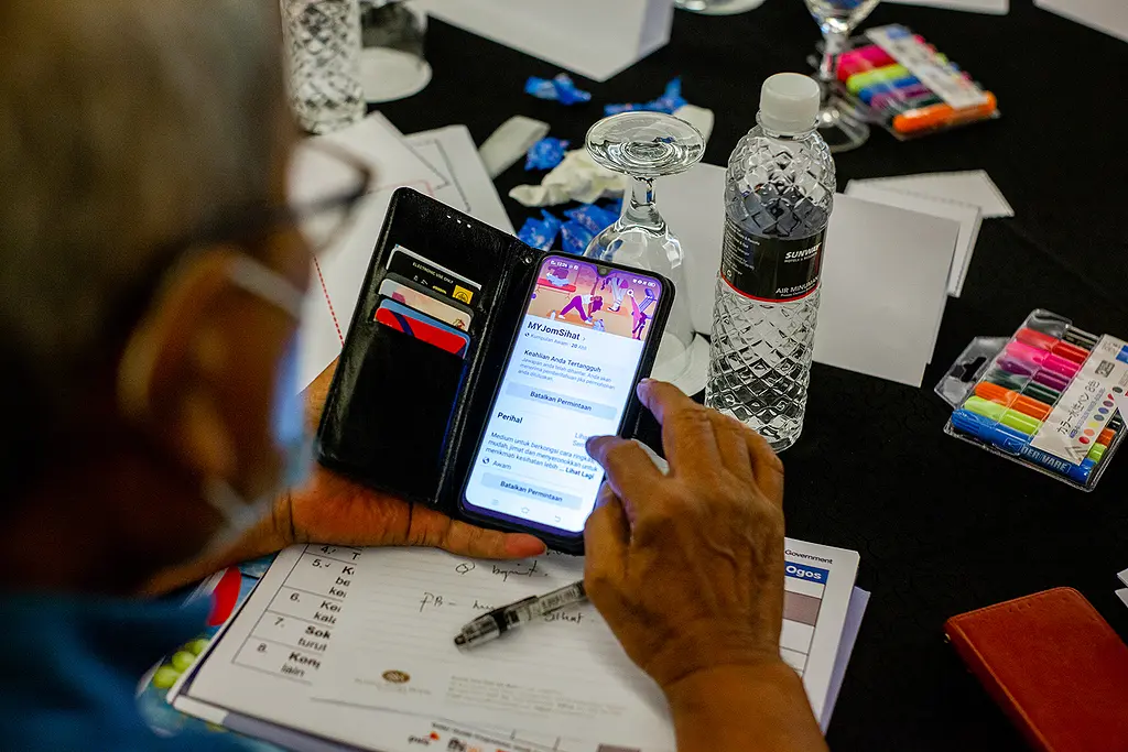 A man uses a smartphone to check out an online community sponsored by Better Health Malaysia.