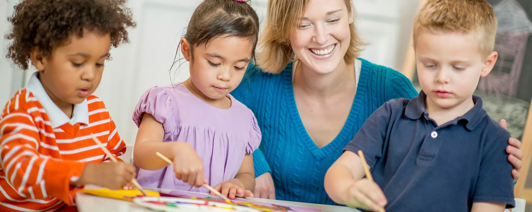 Preschool children paint with a teacher