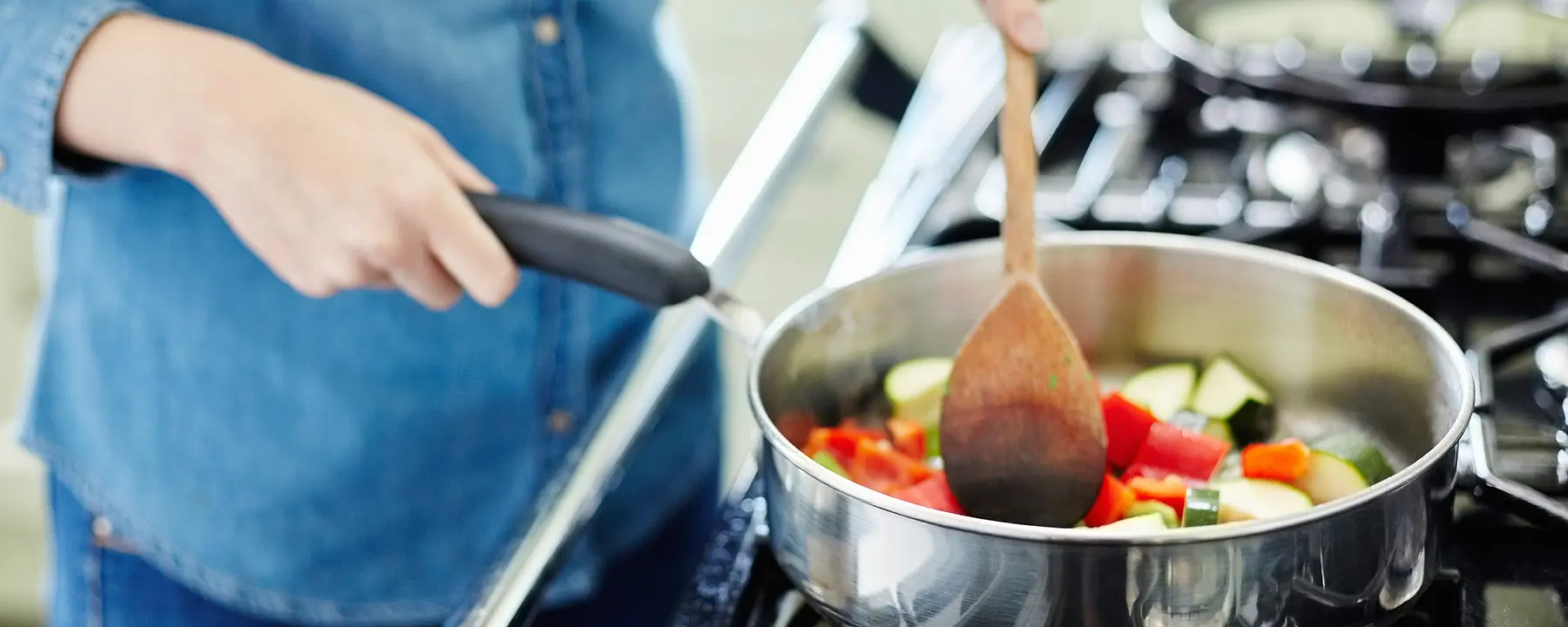 A woman cooks vegetables on a stovetop