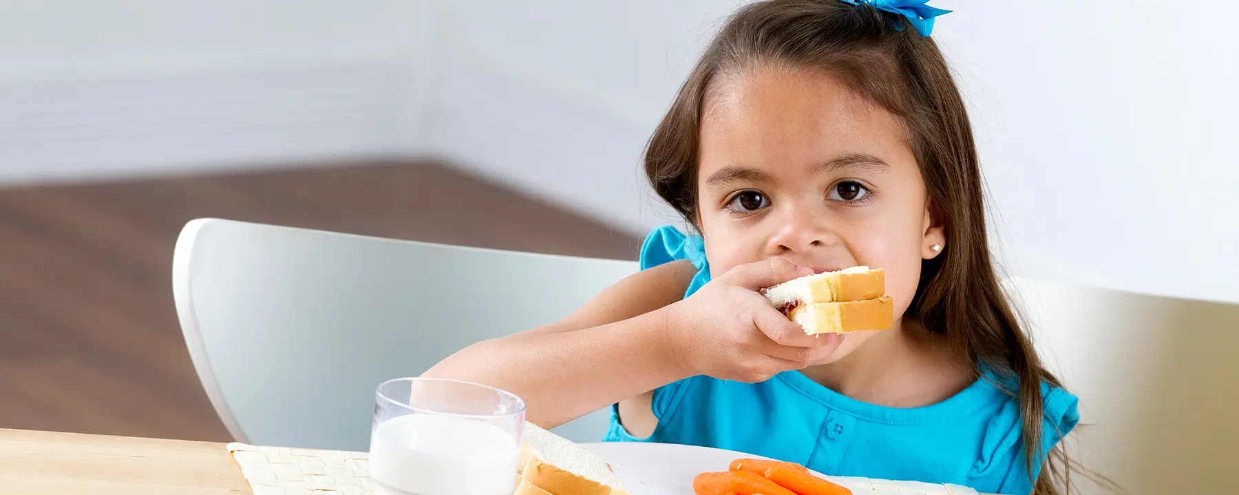 A preschool girl eating a sandwich