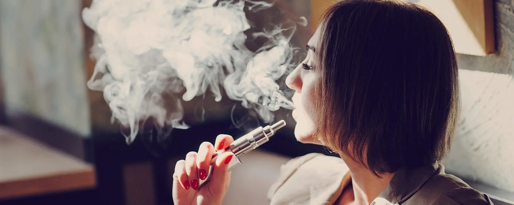 A woman vaping with an e-cigarette indoors