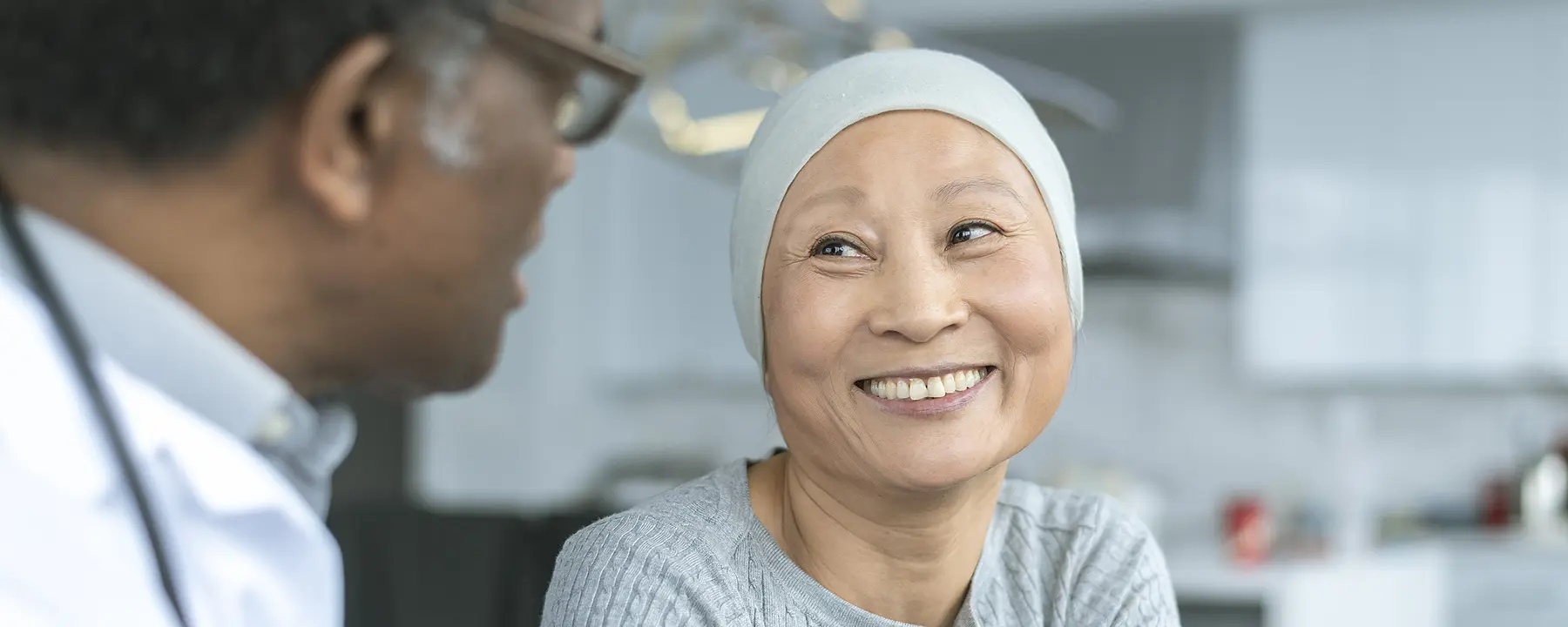 A cancer patient smiles at her doctor.