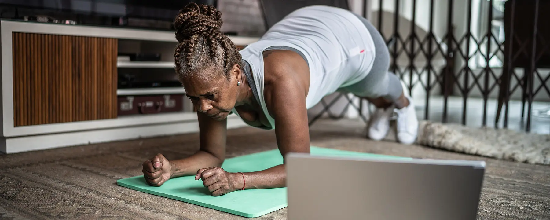 Women exercising on a mat next to her computer