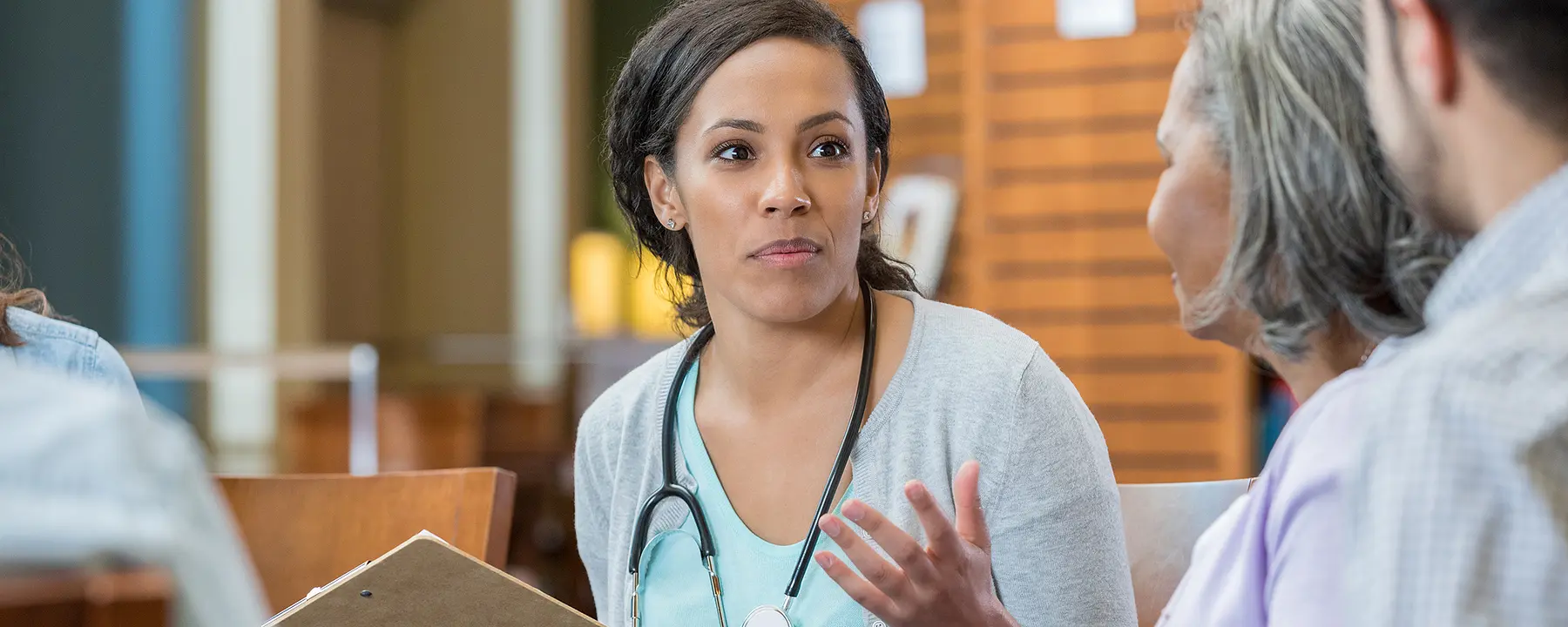 An African-American woman doctor talks with members of a health care team.