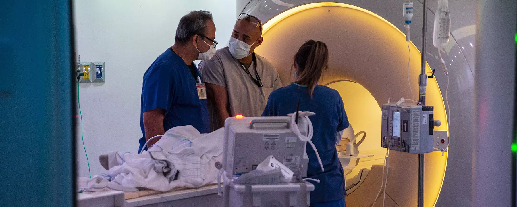 Medical personnel help a patient prepare for an MRI at a military hospital.