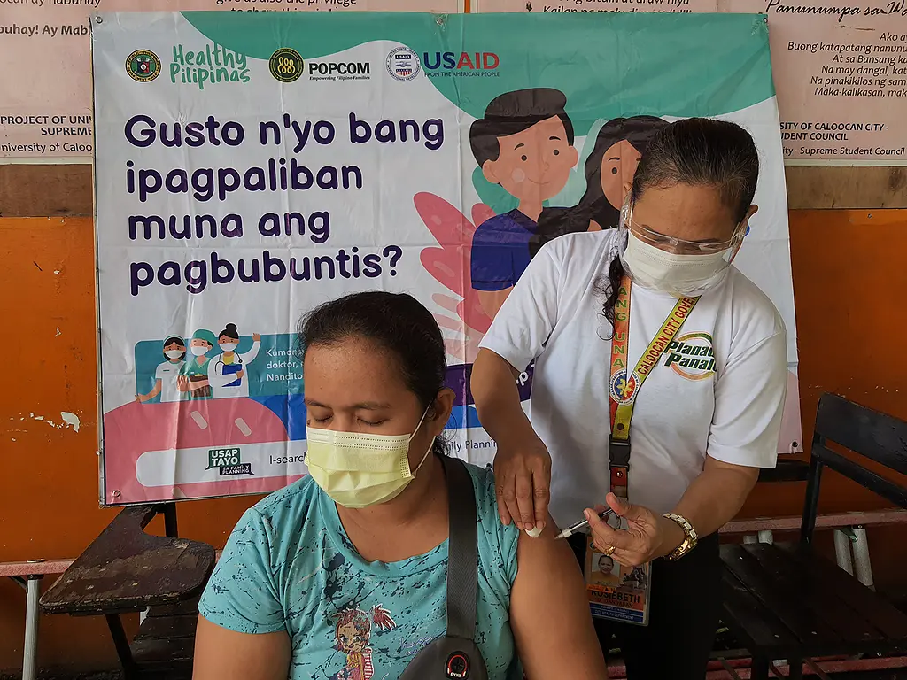A woman receives an injection at a ReachHealth event in the Philippines.