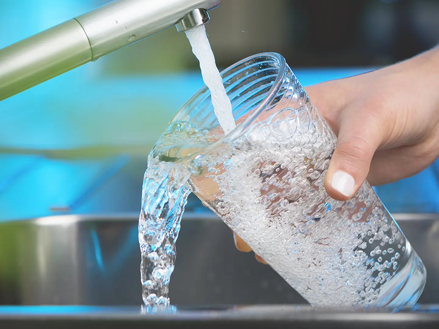 Closeup of someone filling a glass of water from a faucet.