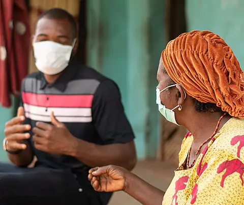 Two people with masks having a conversation