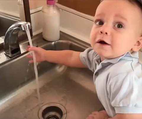 Child reaching into sink