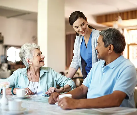 Two nursing-home residents, a woman and a man, talk with a female staff member.