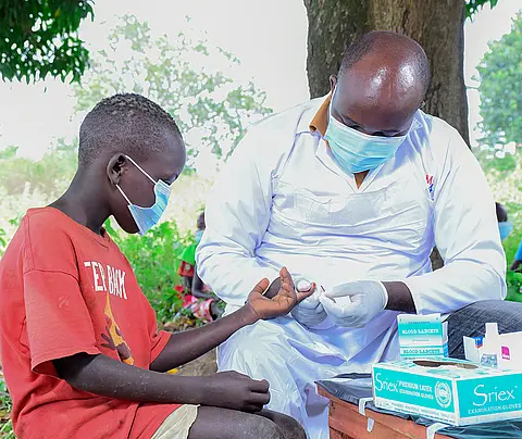A health worker collects blood samples from a child during an LF transmission assessment survey in Uganda.
