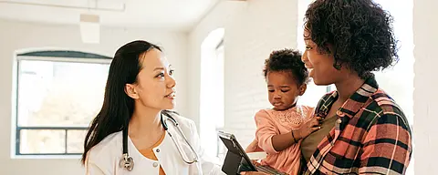 A female pediatrician talks with an African-American mother and her toddler.