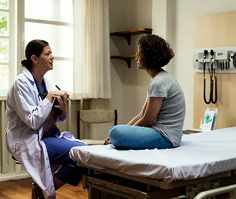 A woman doctor consults with her patient about symptoms