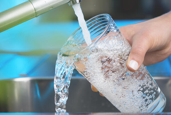 Closeup of someone filling a glass of water from a faucet.