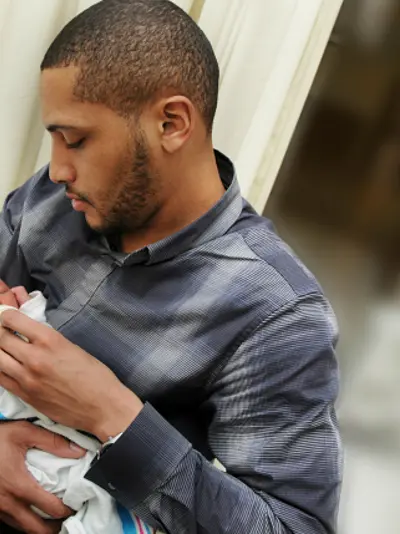 A father holds a newborn baby in a hospital room